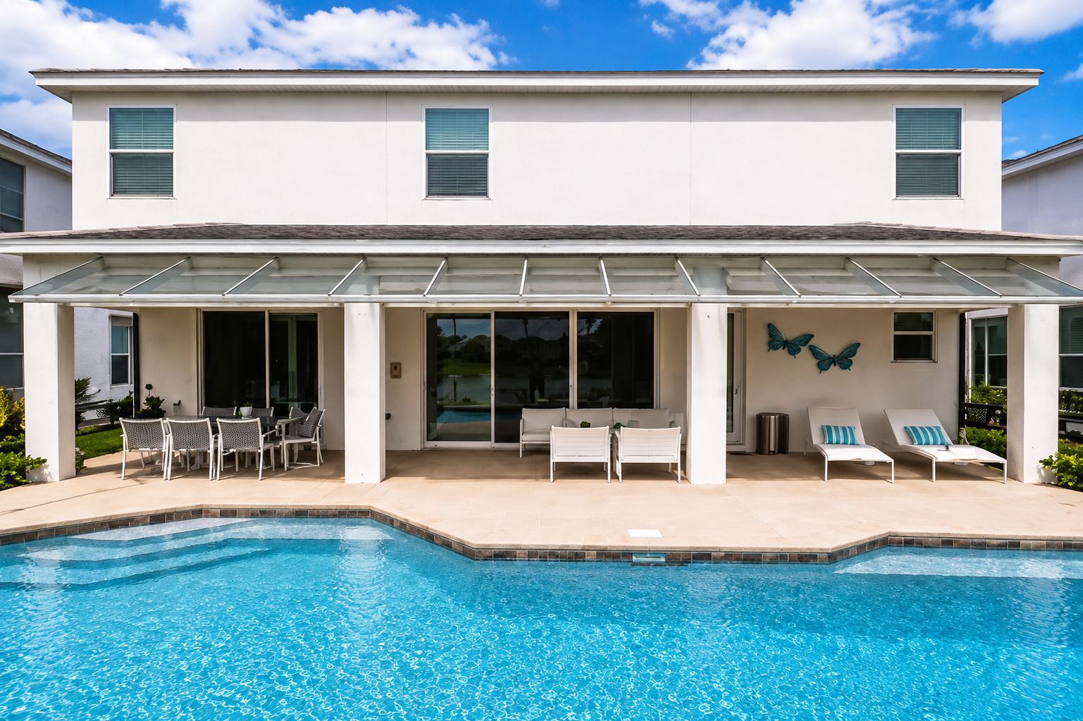 Modern white house with pool, patio furniture, and covered outdoor seating area