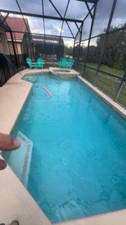 Resort pool with turquoise water, lounge chairs, and screened enclosure