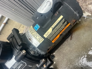 Black air compressor tank with motor mounted on top, positioned on concrete ground