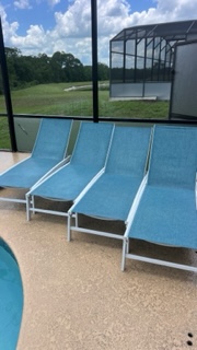 Blue lounge chairs on patio overlooking pool and screened lanai