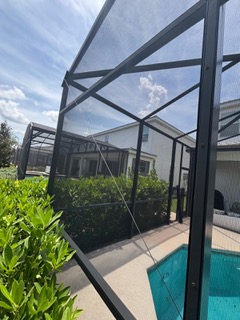 Black pool enclosure screening with view of backyard pool and landscaping