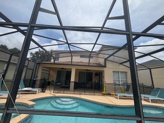 Residential pool with screened enclosure and two-story home in background