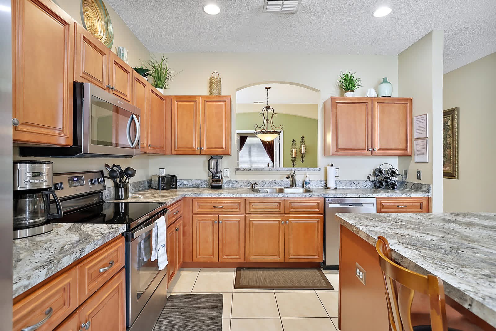 Spacious kitchen with warm wood cabinets, granite countertops, stainless steel appliances and island seating