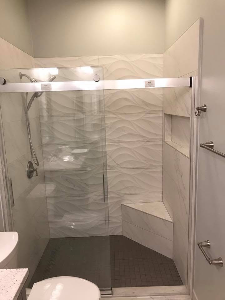 Modern bathroom with walk-in shower, glass enclosure, marble tile walls, and brushed nickel fixtures