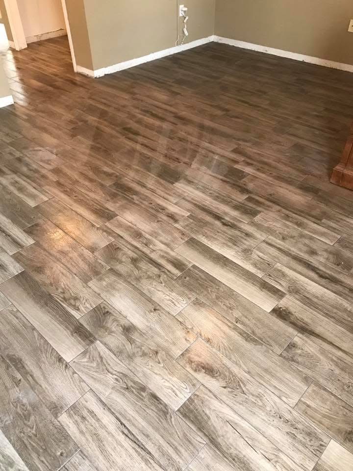 Newly installed laminate wood flooring in light brown tones laid in staggered pattern in empty room