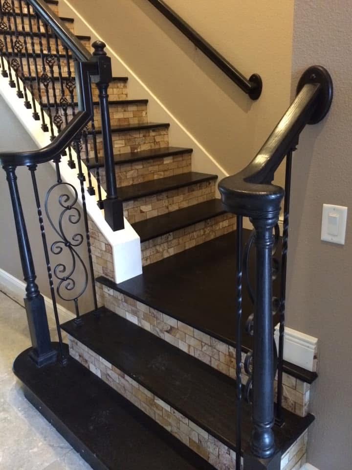 Modern staircase with black wrought iron railings, brick risers, black treads, and brass handrails