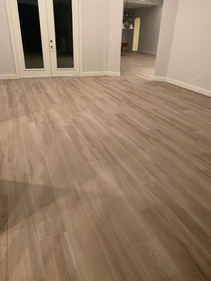 Empty living room with light wood-grain laminate flooring and white walls
