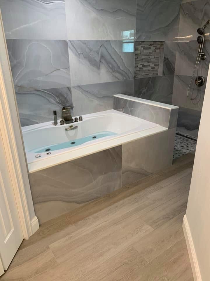 Modern bathroom with soaking tub, marble tile walls, walk-in shower, and wood-look flooring