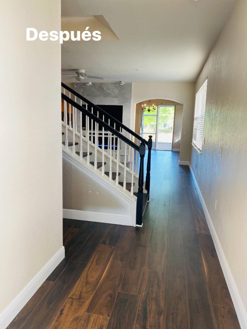 Upstairs hallway with dark wood flooring, white and black stair railing, and natural light from arched doorway