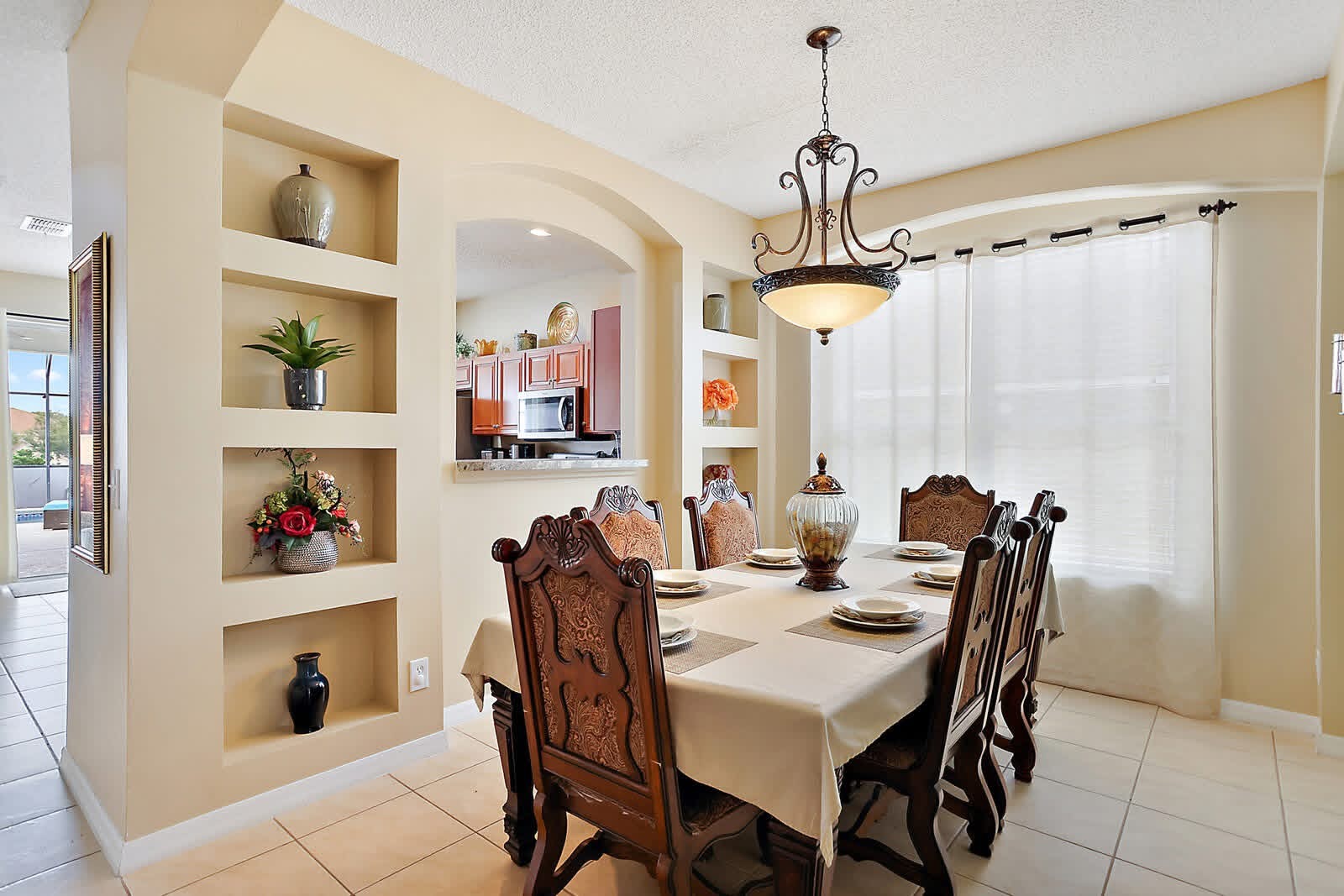 Elegant dining room with cream-colored walls, wooden chairs, and built-in shelving displaying decorative items