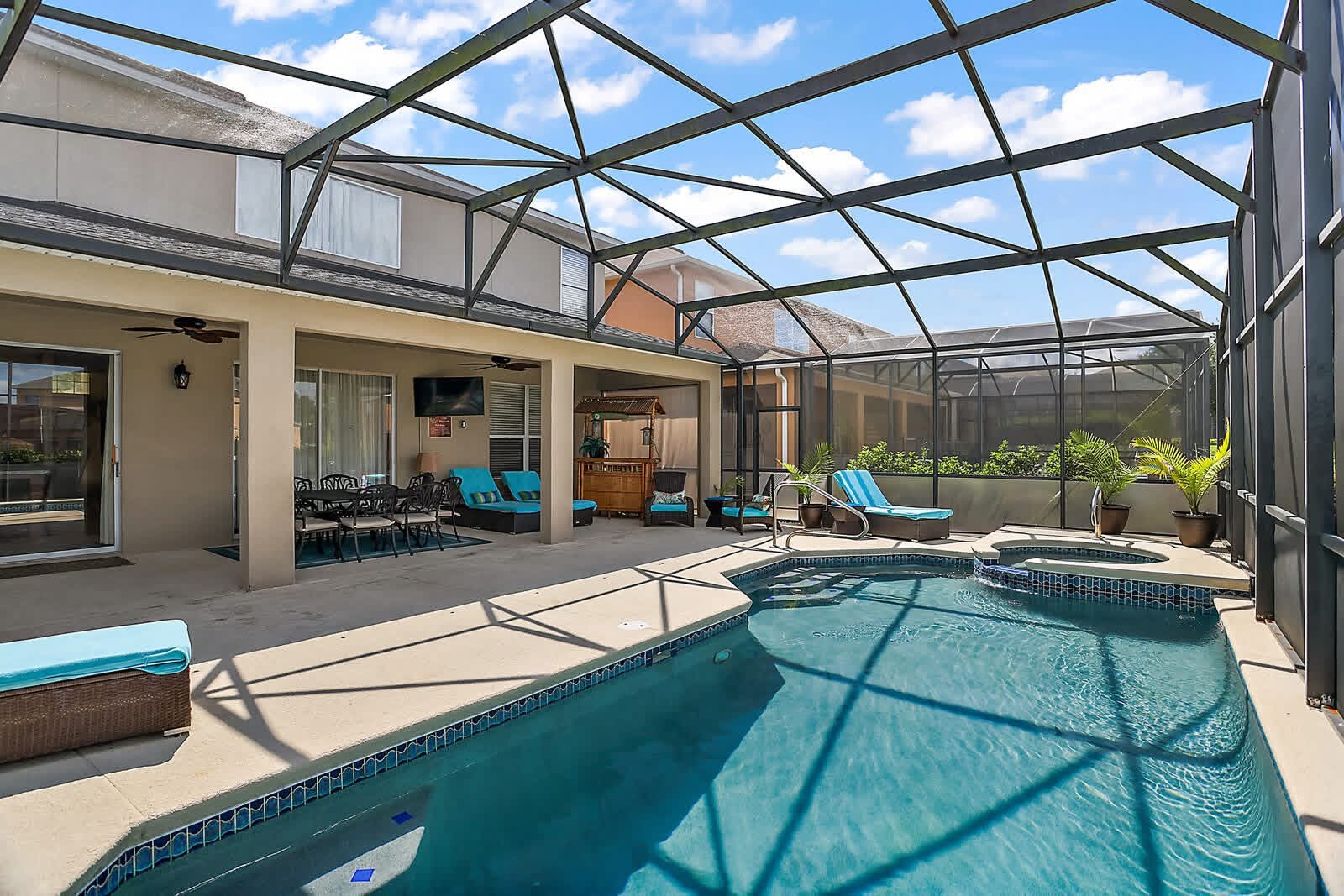 Screened pool and spa with lounge seating and lanai overlooking residential home
