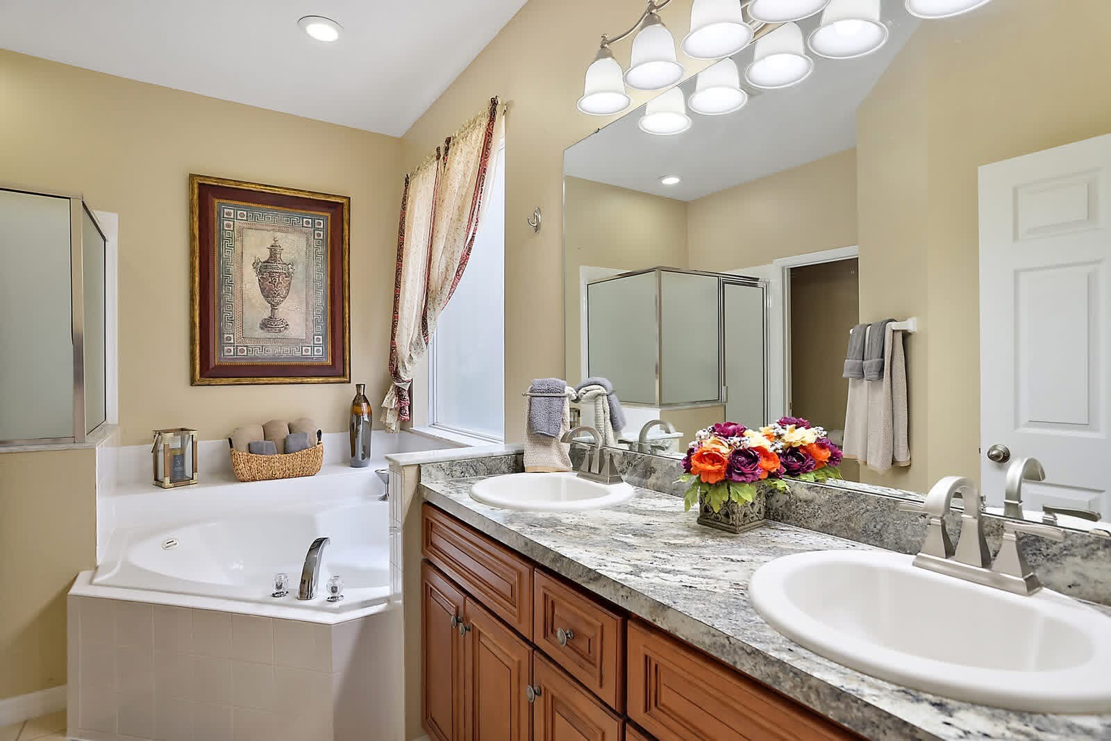 Luxury master bathroom with dual vanities, marble countertop, soaking tub, and glass shower enclosure