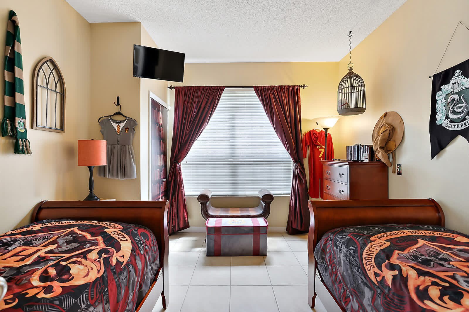 Harry Potter themed bedroom with two beds, burgundy curtains, and Hogwarts house decorations