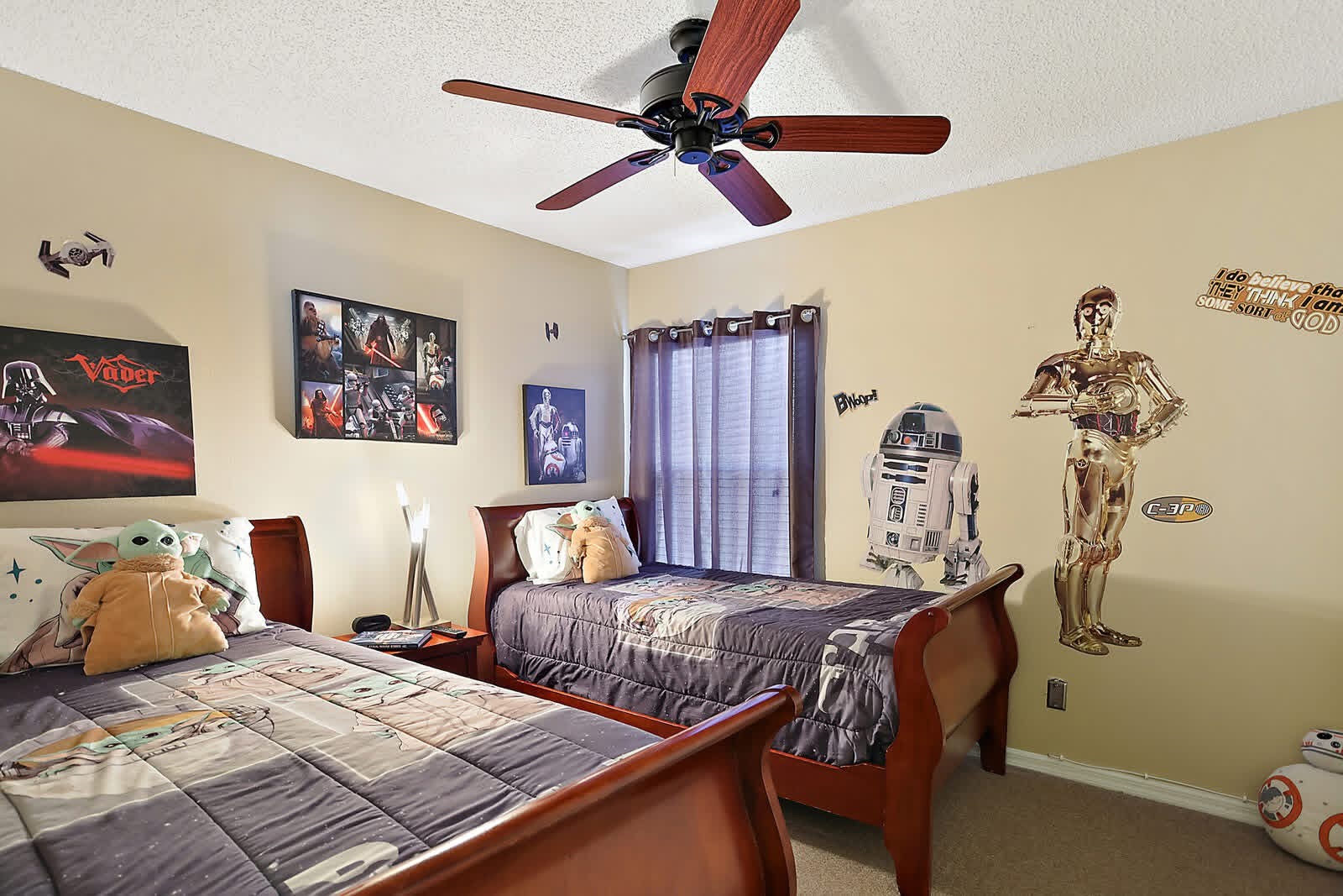 Star Wars themed bedroom with two beds, character posters, R2-D2 and C-3PO figures, and ceiling fan