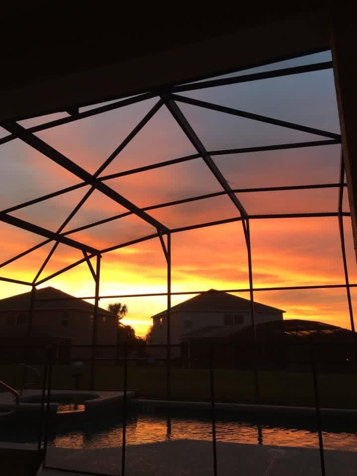 Sunset view through a screened patio structure overlooking residential homes